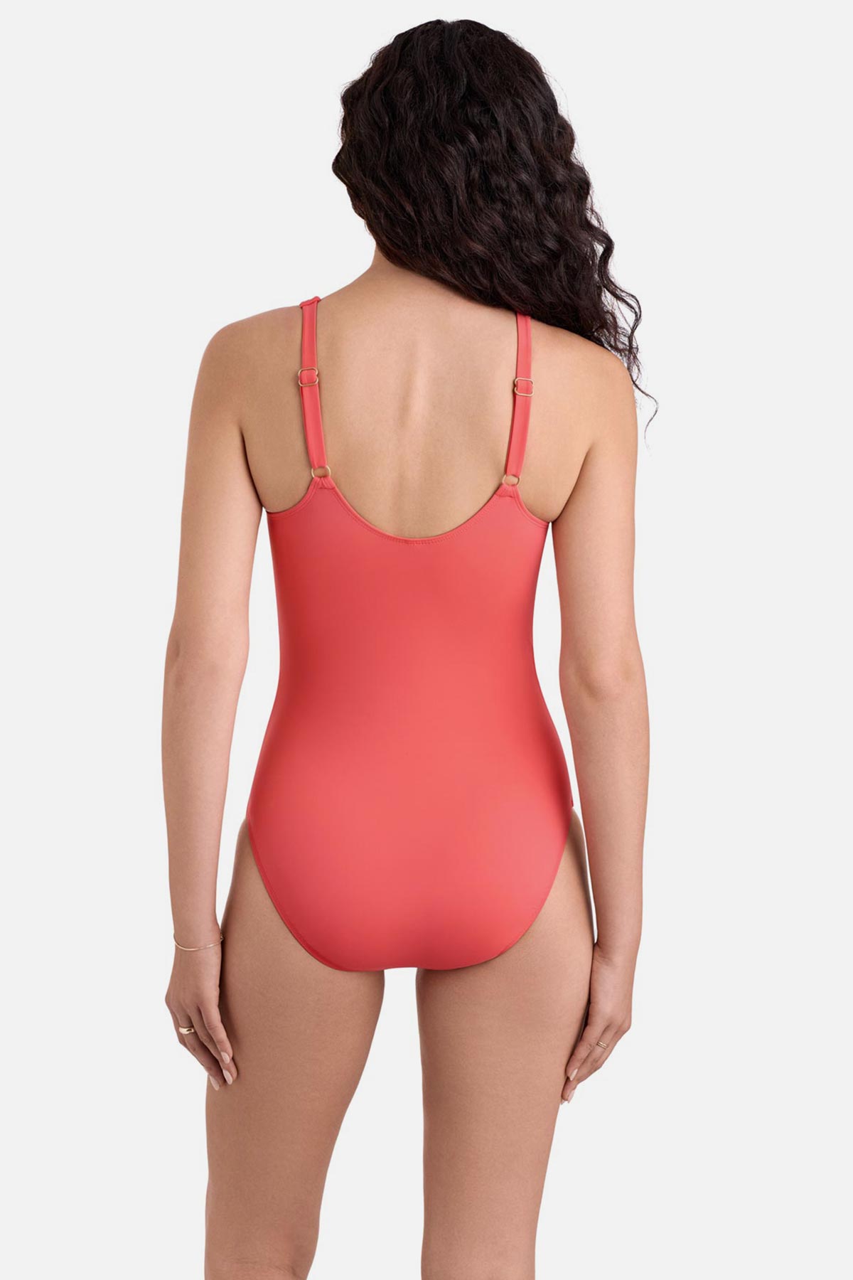 Woman turned away wearing a coral pink one-piece swimsuit 